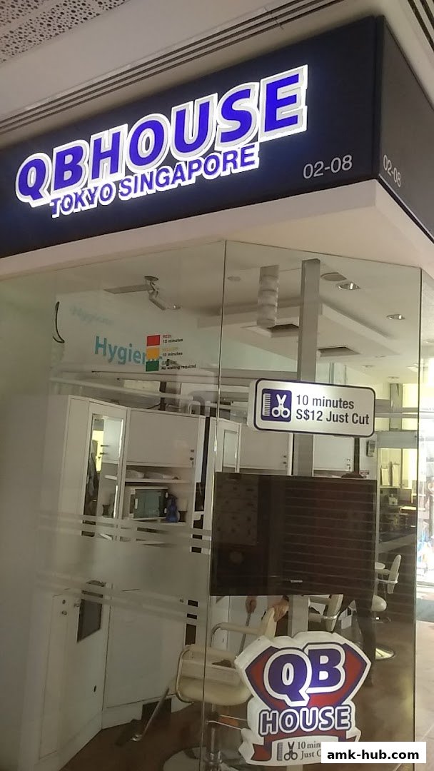 The exterior of QB House, a hair salon, with its prominent signage and a sign advertising a quick haircut.