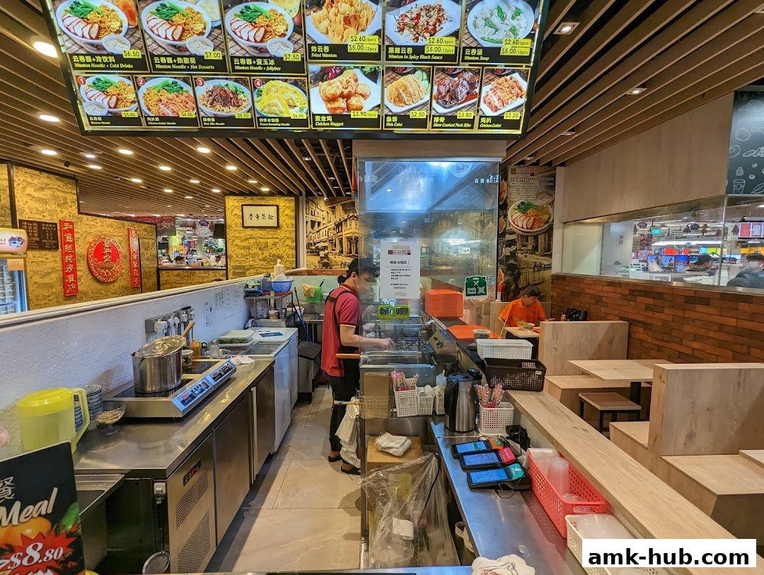 Interior view of Pontian Wanton Noodle shop with a menu board and staff preparing food.