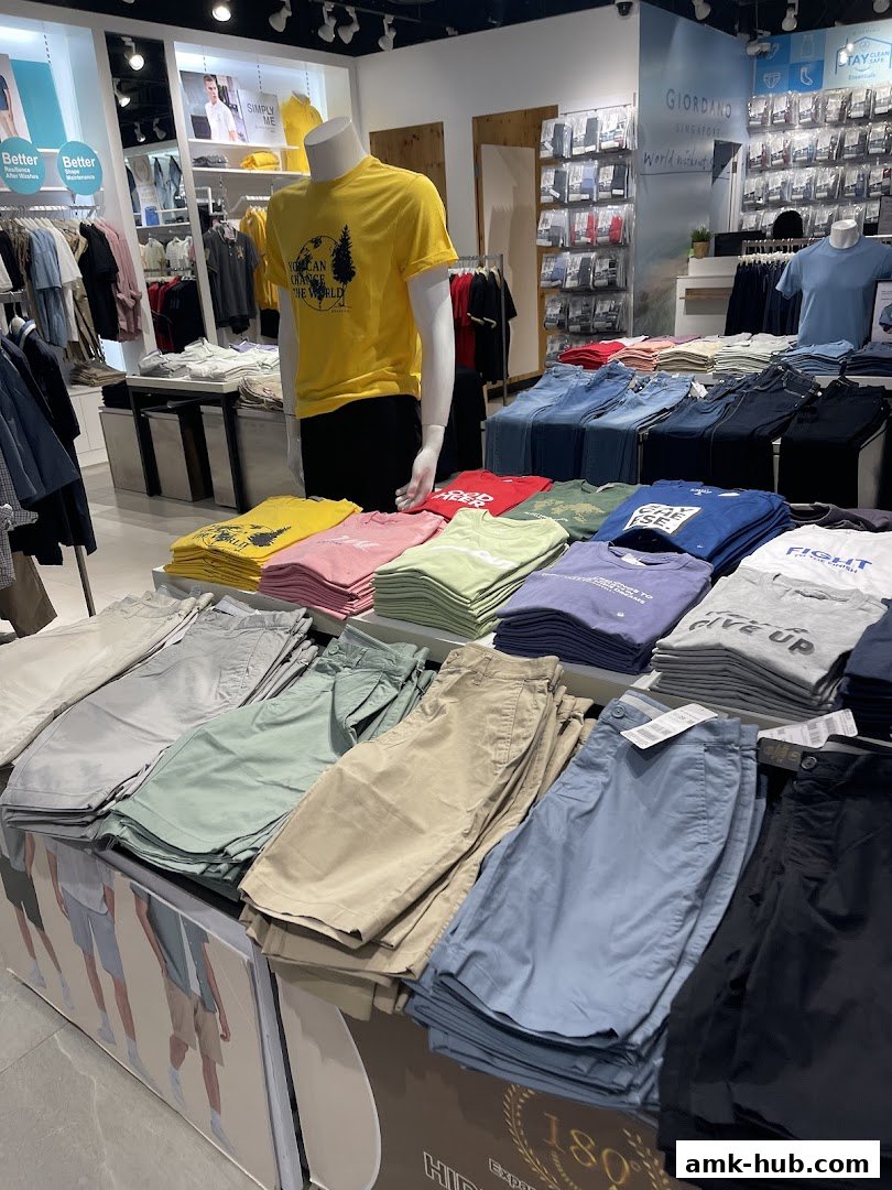 A well-lit retail store interior showcasing folded t-shirts and shorts in various colors.