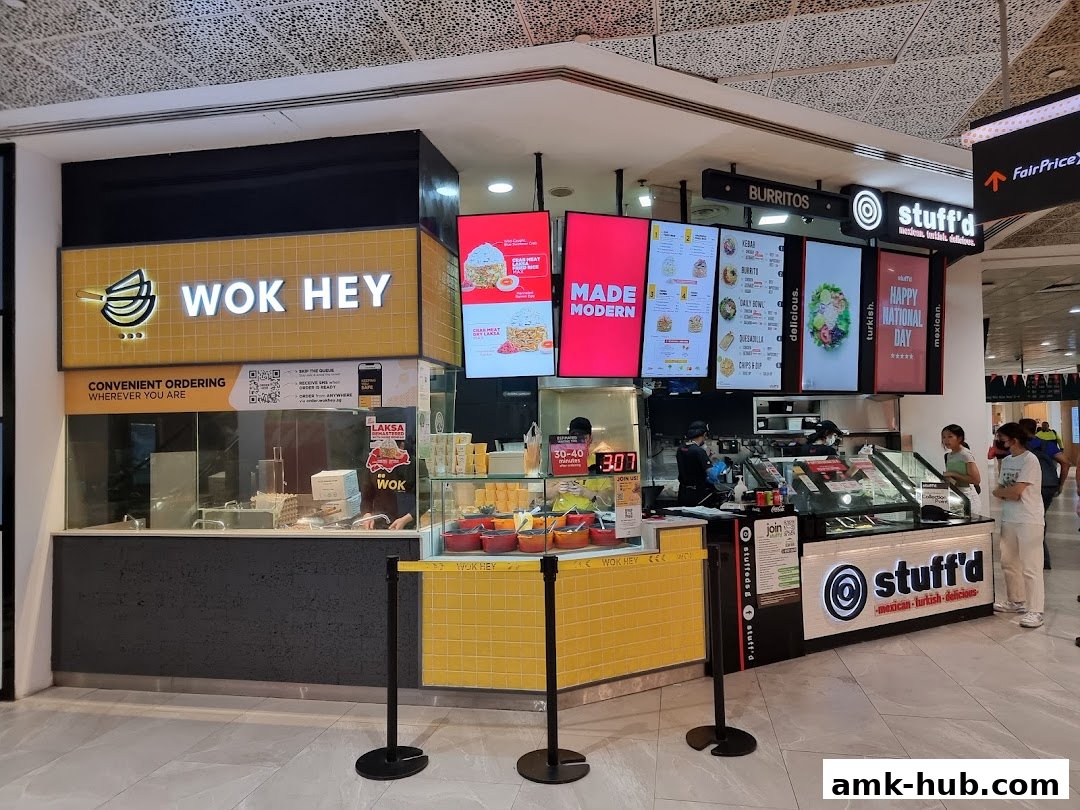 The Wok Hey and Stuff'd food stalls in a shopping mall with digital menus and staff serving customers.