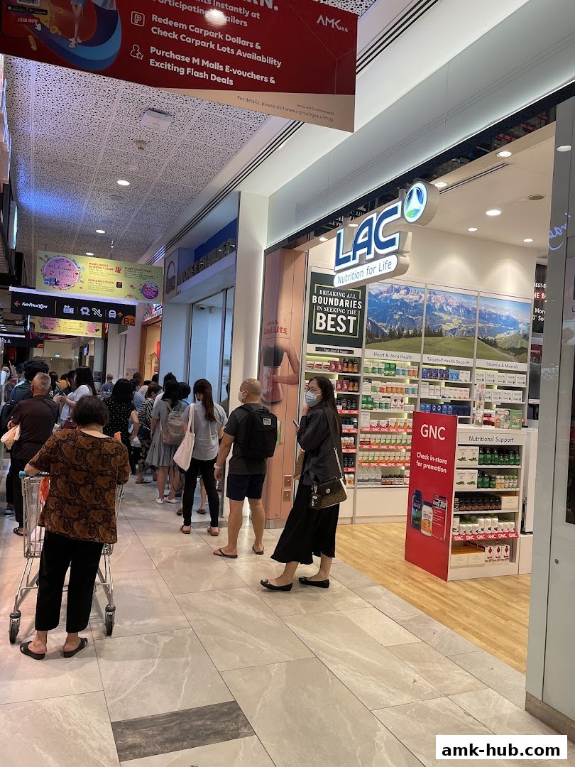 A LAC Nutrition store with a display of health products and a queue of customers outside.