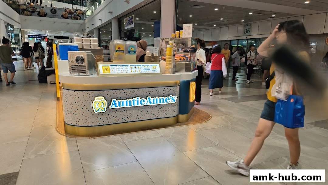 Auntie Anne's pretzel kiosk in a shopping mall with customers and staff.