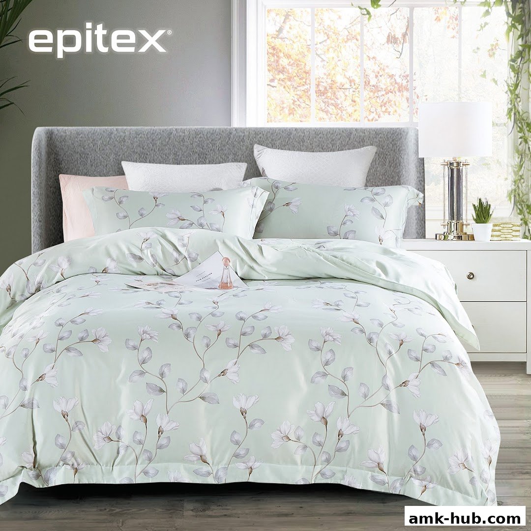 A beautifully made bed with light green floral bedding and a grey headboard.