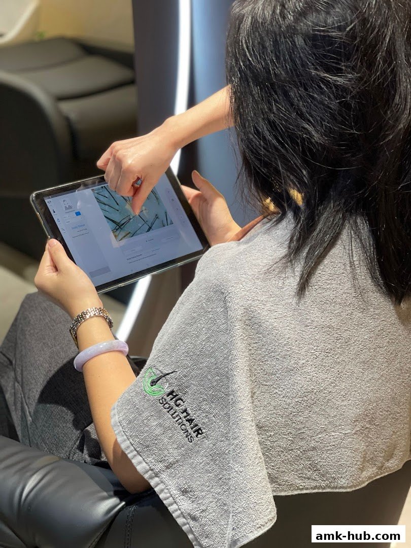 A client consults with a stylist on a tablet showing hair analysis results.