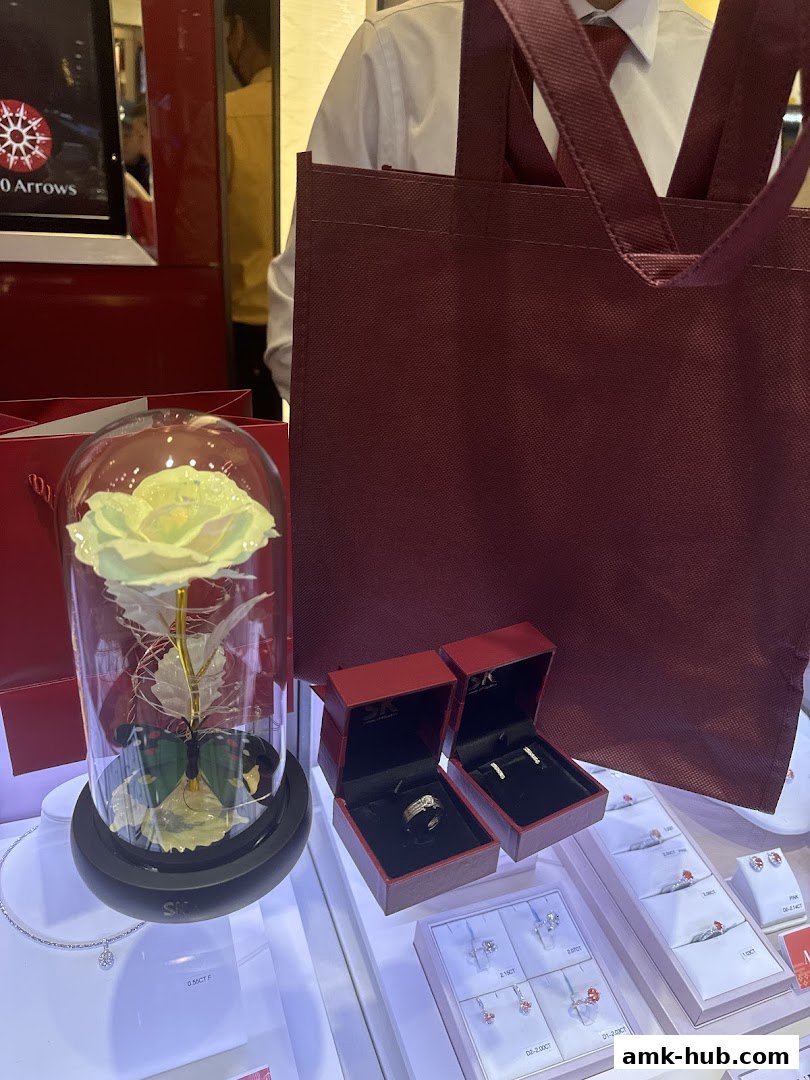 SK Jewellery display featuring a preserved rose, rings, earrings, and a shopping bag.