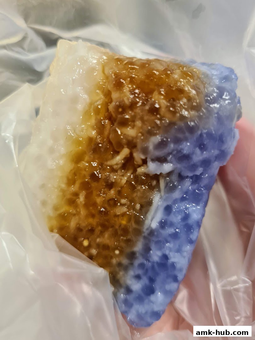 A close-up of a colorful, sweet dessert with a jelly-like texture and shredded coconut.
