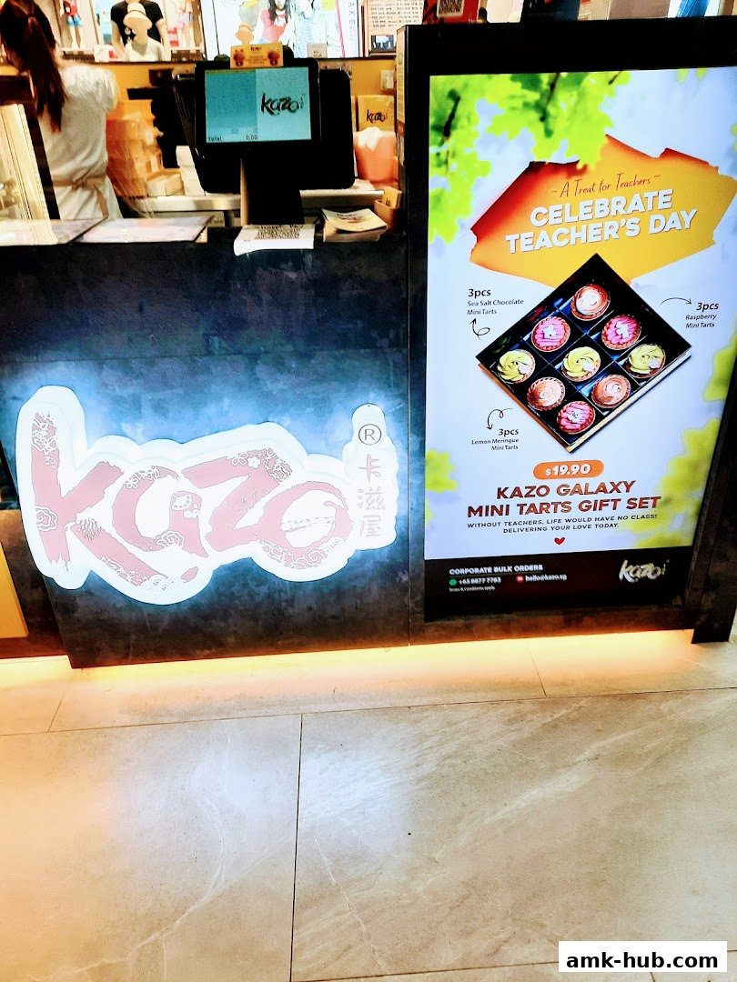 The Kazo shop front features a prominent logo and a digital display showcasing a Teacher's Day gift set.