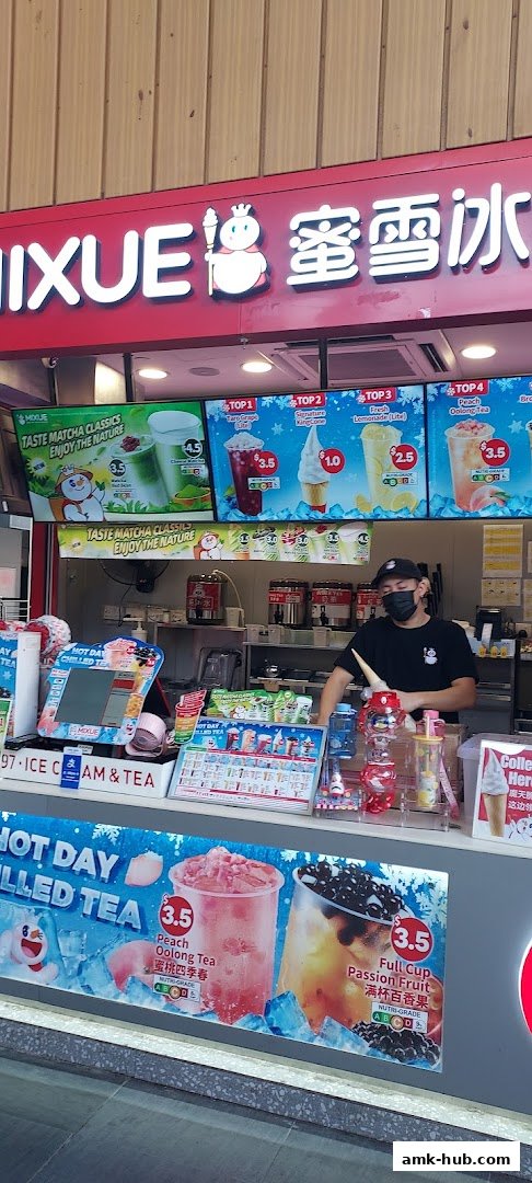 A shop counter with a staff member serving drinks and ice cream, featuring colorful menu displays.