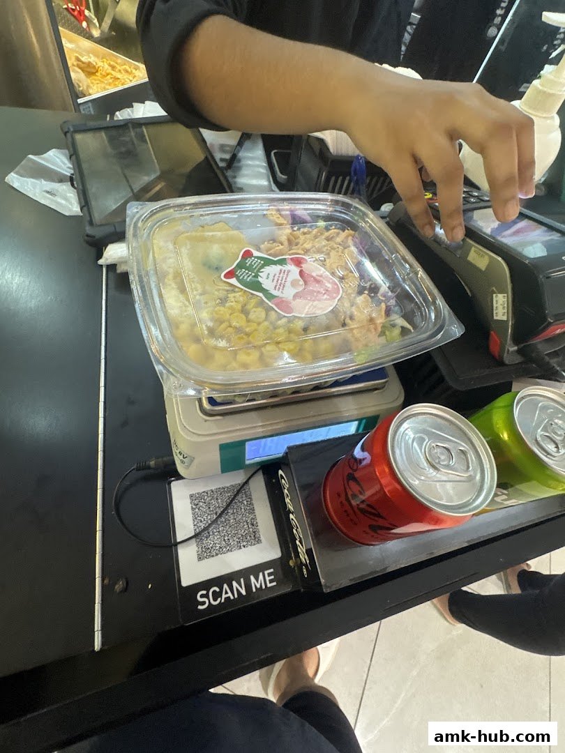 A customer is paying at the counter with a meal and drinks.