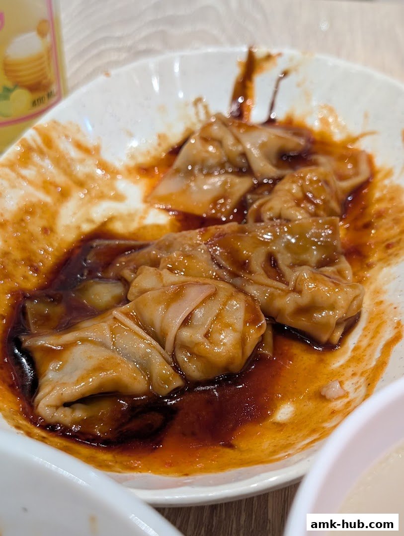 A close-up shot of delicious wanton noodles in a savory sauce.