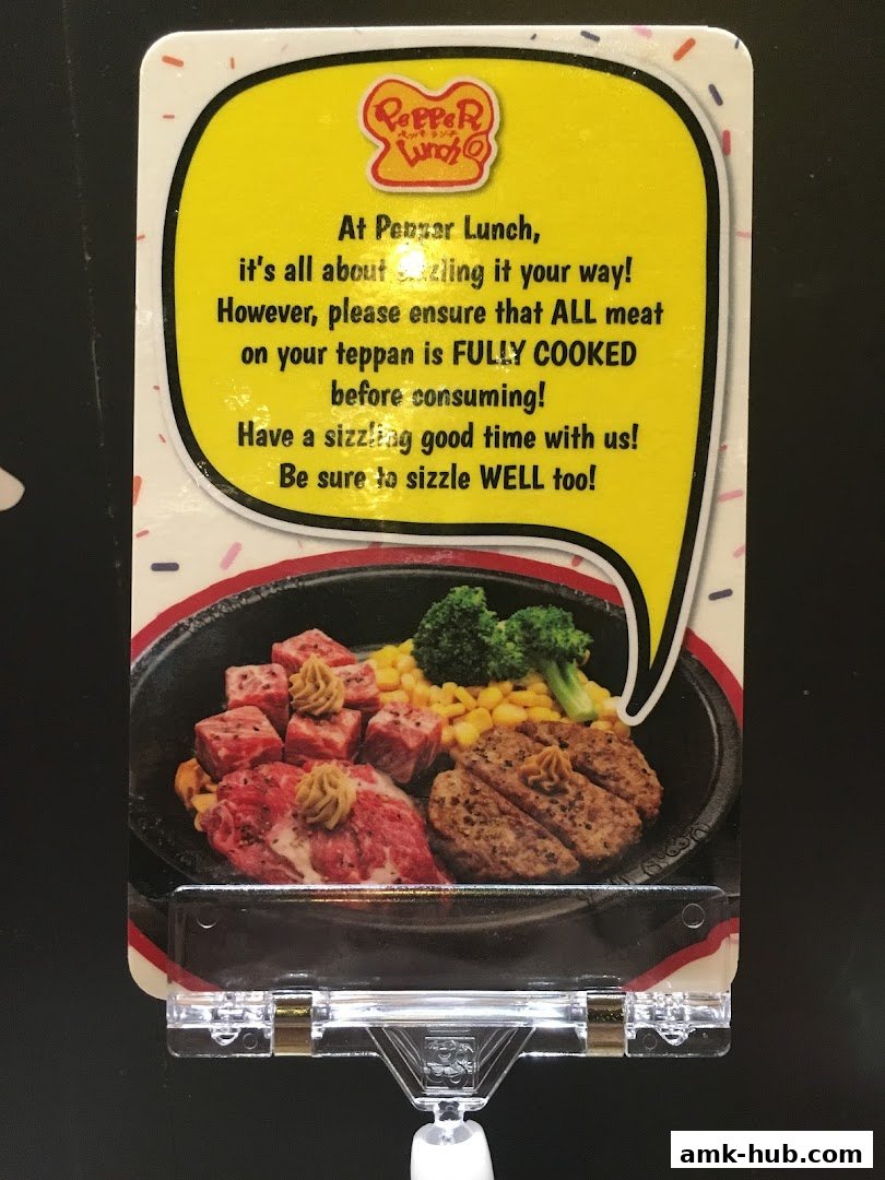 A sign for Pepper Lunch with a picture of sizzling steak and a message about cooking meat.