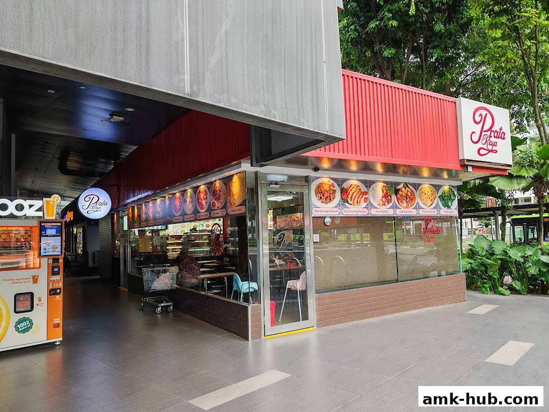 The exterior of Prata Raya restaurant with a red facade and a display of food items.
