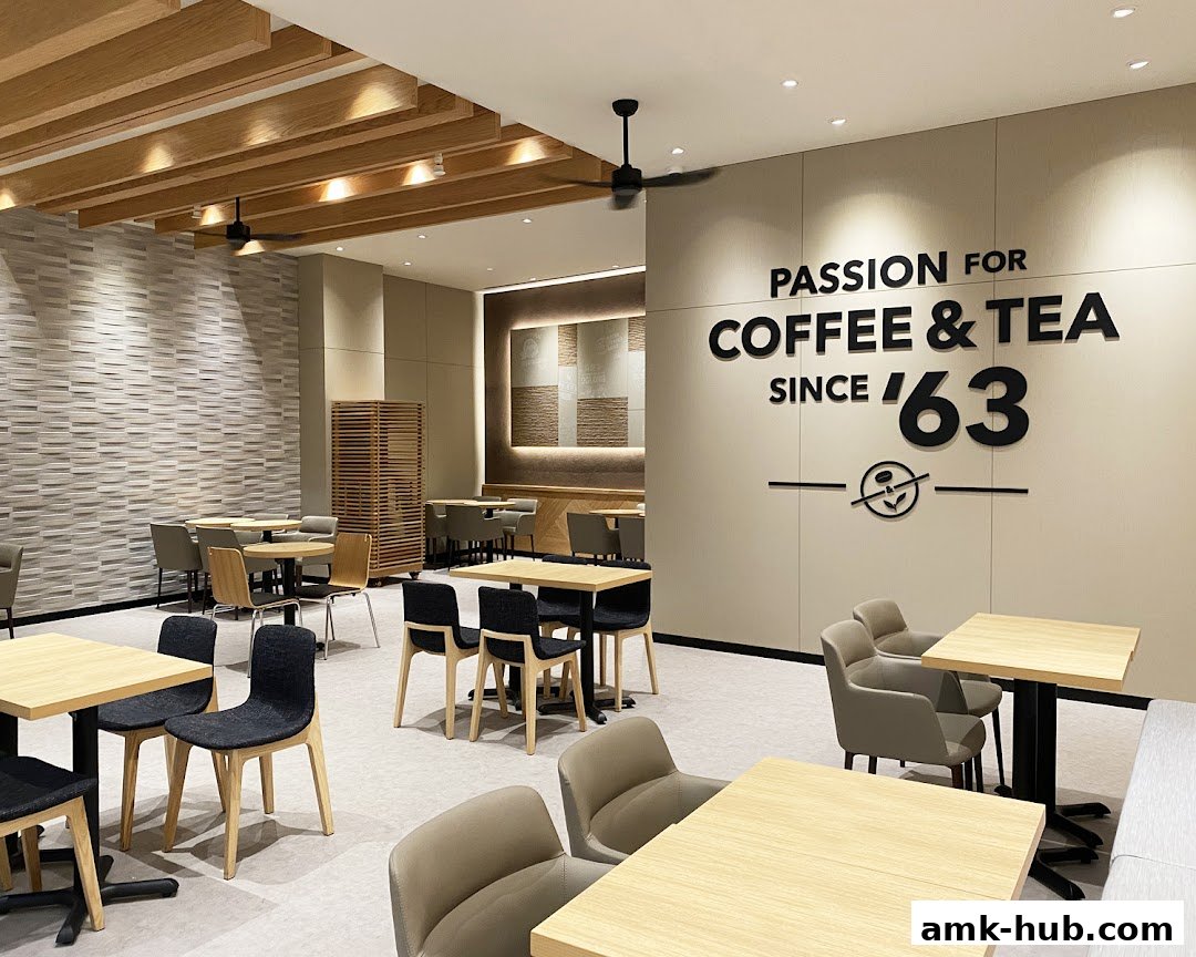 Interior of a modern coffee shop with tables, chairs, and a prominent "Passion for Coffee & Tea Since '63" sign.