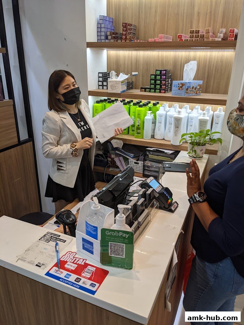 Staff member at the counter of a hair salon, with shelves of hair products in the background.