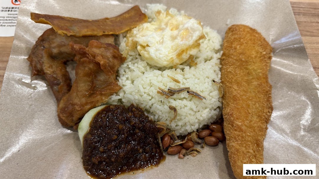 A plate of Nasi Lemak with fried chicken, fried fish, fried egg, and sambal.