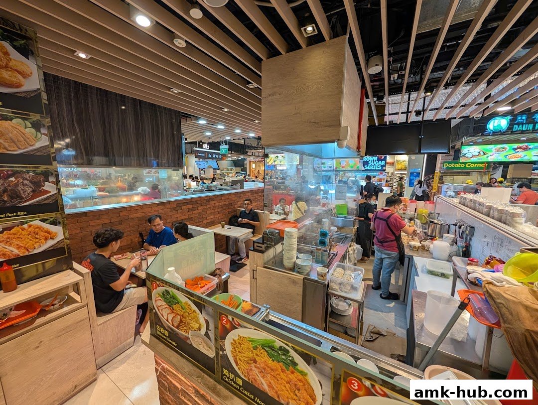 A busy food stall with customers dining and staff preparing food.