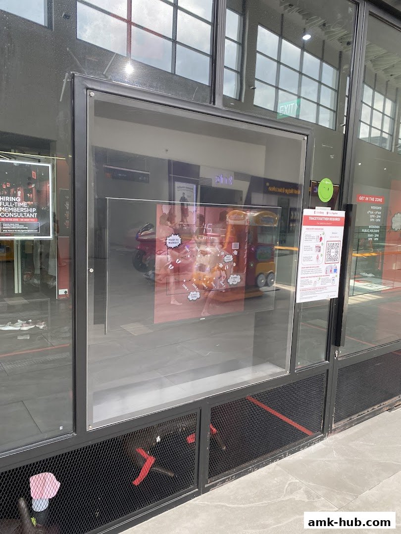 The exterior of a shop with a large glass window displaying promotional material and operating hours.