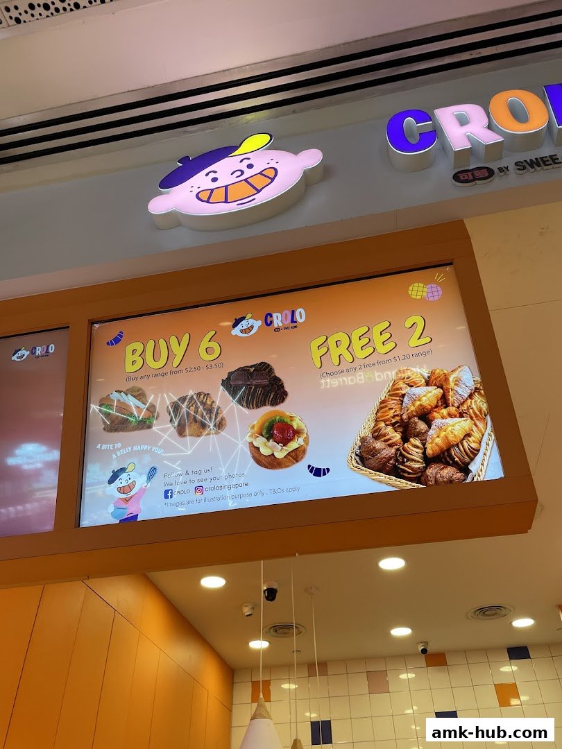 A brightly lit display board showcasing a "Buy 6 Get 2 Free" promotion for pastries at CROLO by Swee Heng.