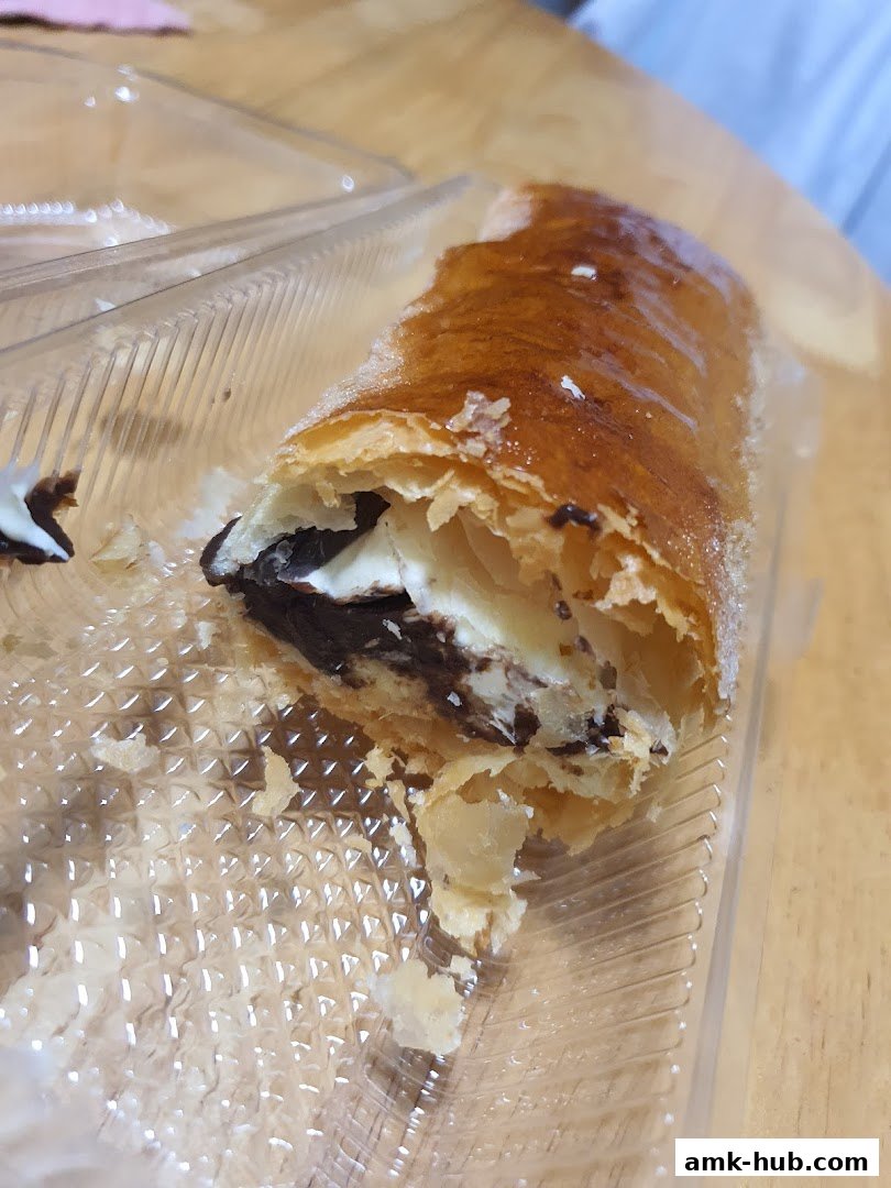 A close-up of a chocolate-filled strudel in a clear plastic container.