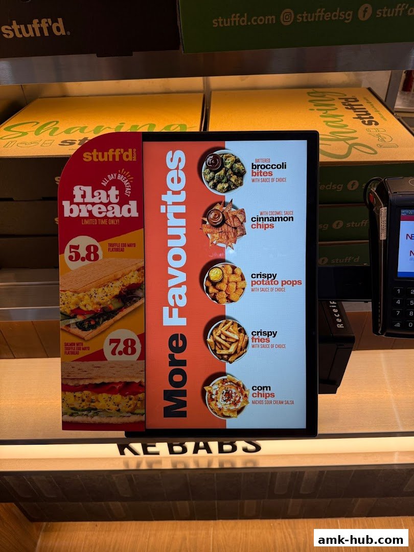 A digital menu board displaying various food items and prices from Stuff'd More.