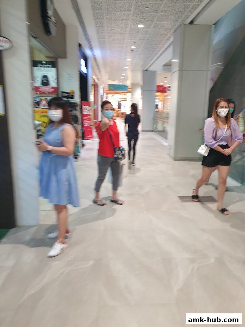 People walking in a mall hallway, some wearing masks.
