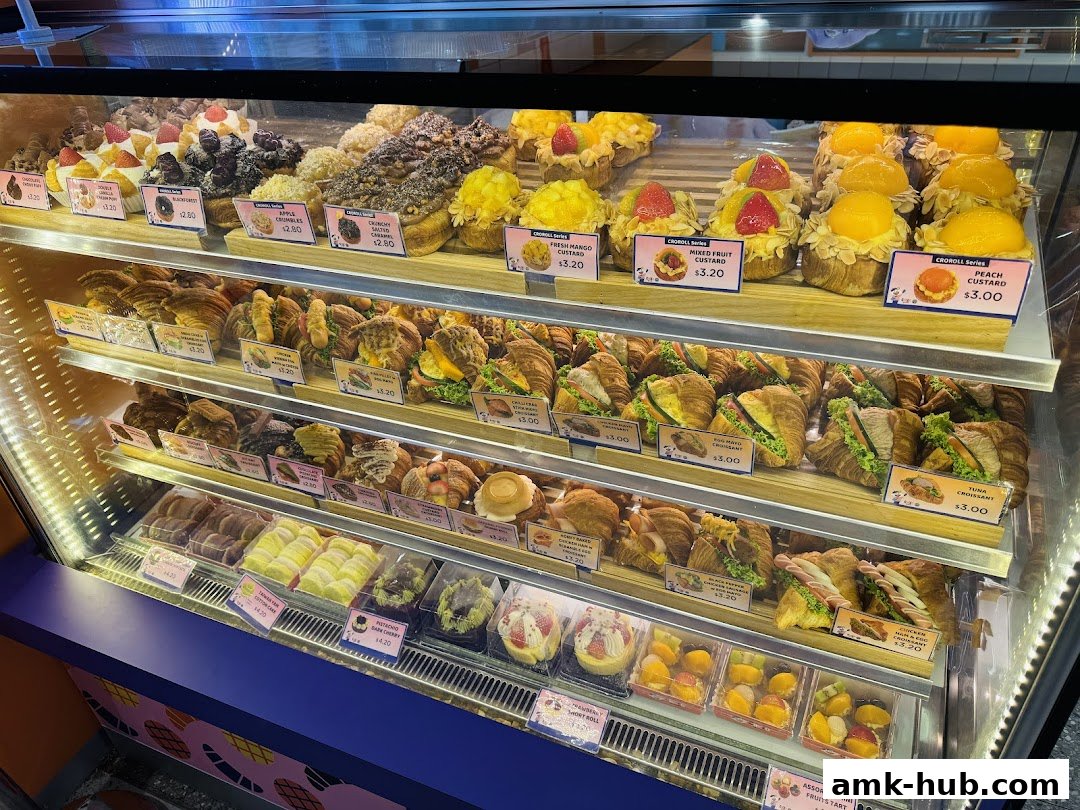 A display case filled with various pastries, croissants, and tarts from CROLO by Swee Heng.