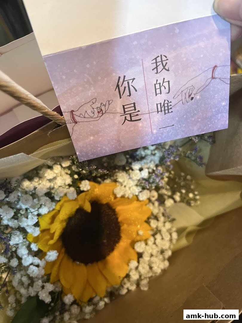A close-up of a sunflower bouquet with a card featuring Chinese text and illustrated hands.