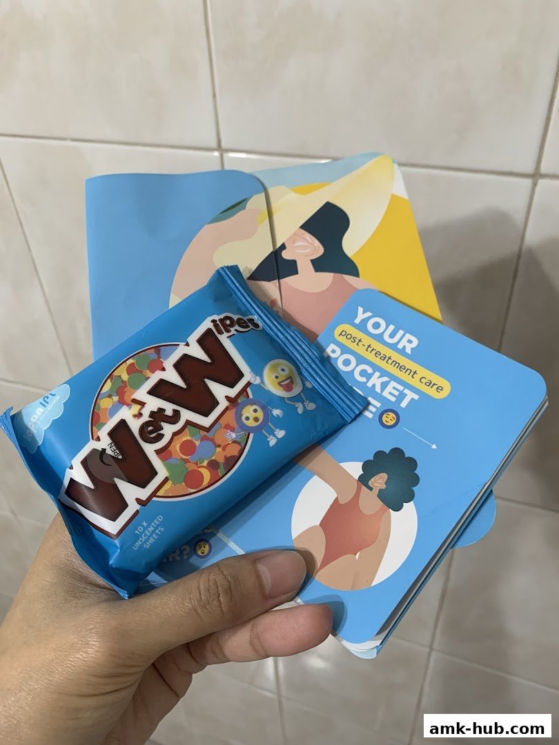 A hand holds a pack of M&M's and a booklet about post-treatment care.