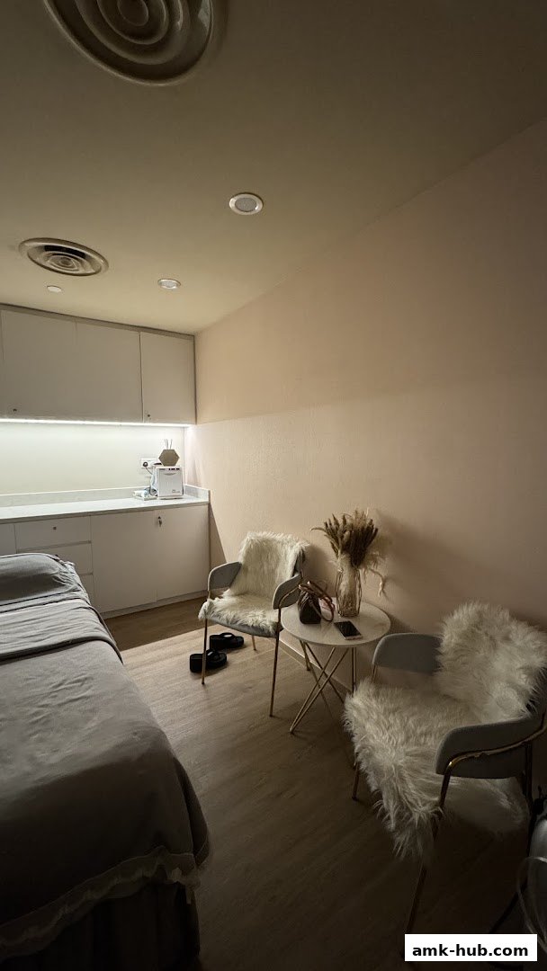 A treatment room with a massage bed, chairs, and a counter with equipment.