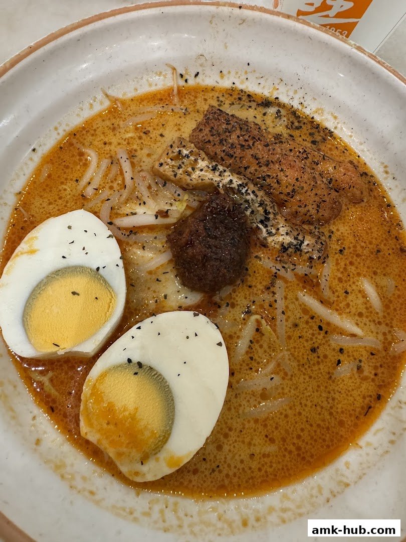 A close-up shot of a delicious bowl of Laksa with half-boiled eggs and fried tofu.