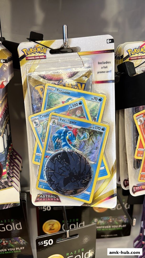 A retail display featuring Pokémon trading card packs with featured cards and a coin.