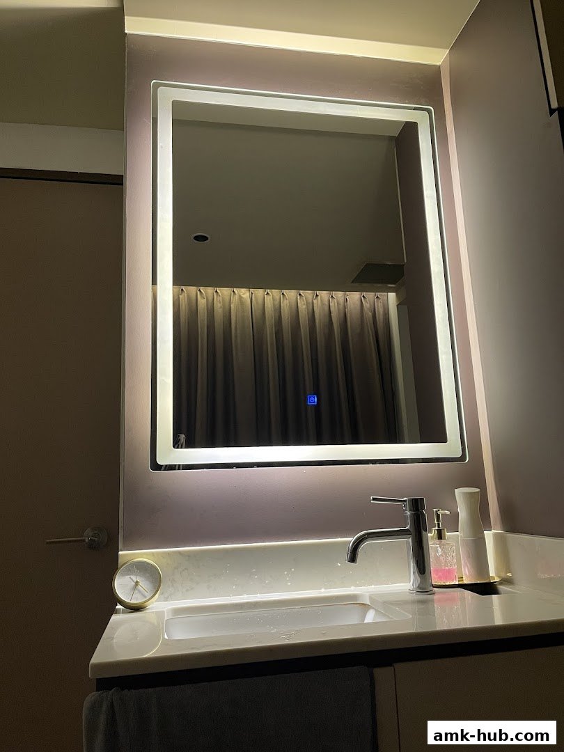 A modern bathroom vanity with a lighted mirror, sink, faucet, and soap dispenser.