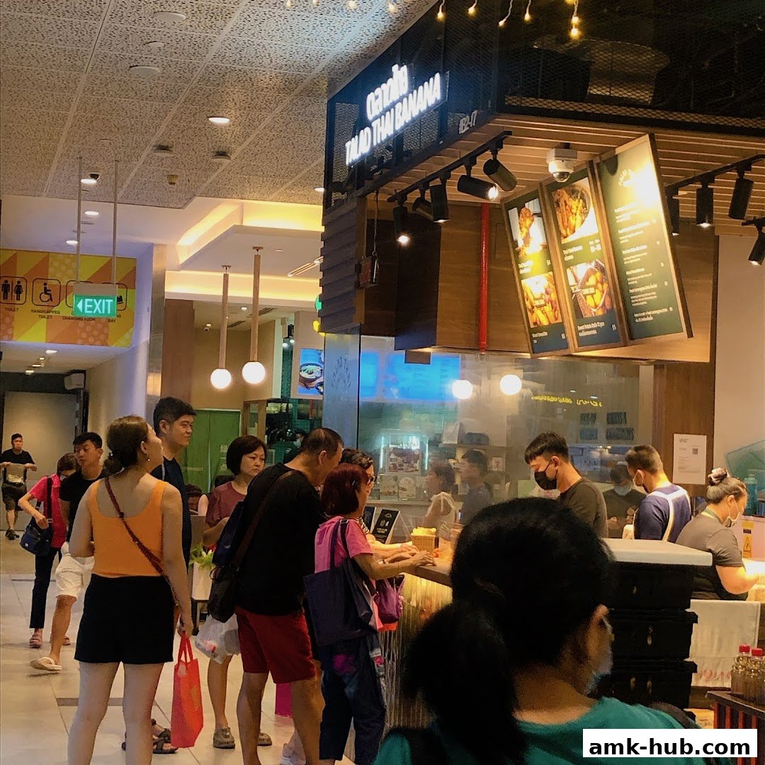 A busy food stall with a queue of customers ordering and staff serving food.