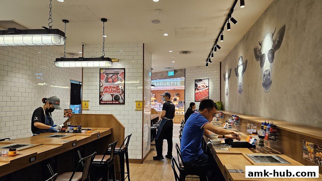 Interior of a Yakiniku Like restaurant with diners at the counter and staff preparing food.