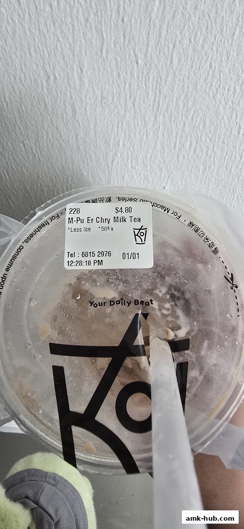 A close-up of a KOI Thé milk tea cup with a label showing the drink name and price.