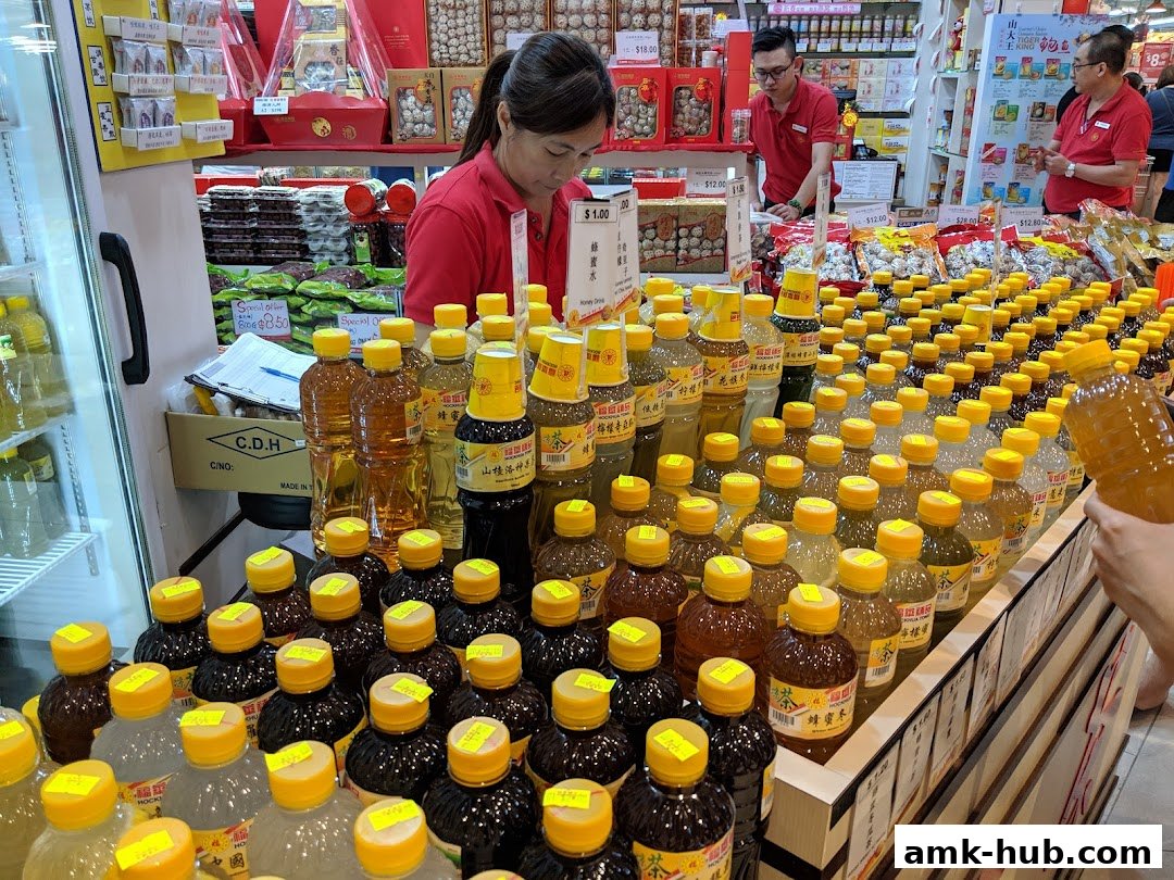 A shop interior displaying rows of bottled drinks and packaged goods, with staff attending to customers.