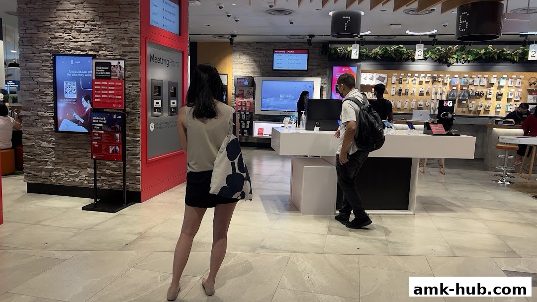 Customers browse electronics and services at a modern Singtel shop with digital displays.