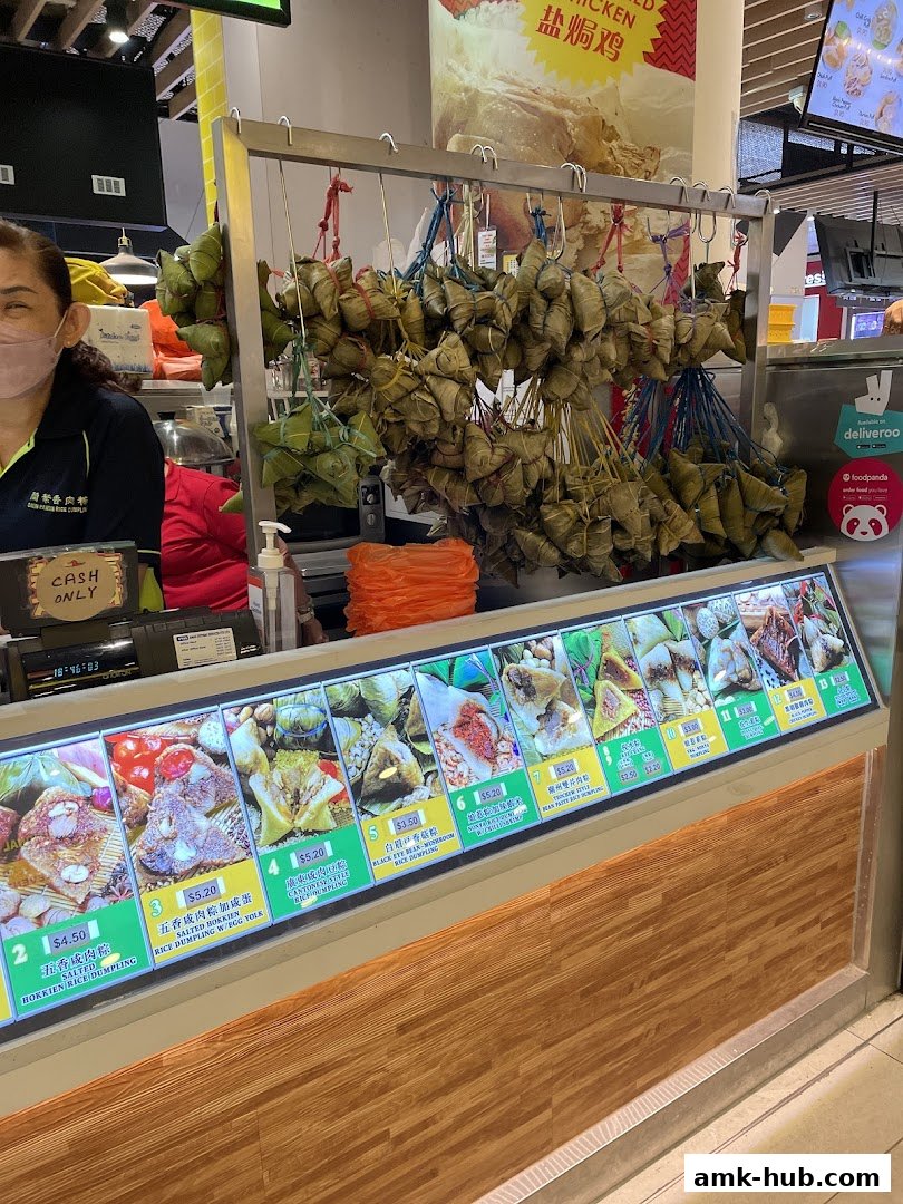 A shop counter displaying various rice dumplings with prices and images, and a selection hanging above.
