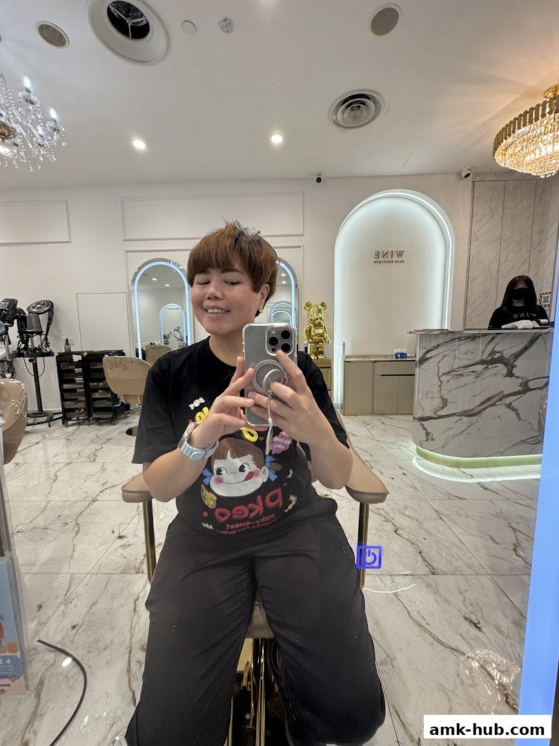 A person takes a selfie in a stylish hair salon, showing off their new haircut.
