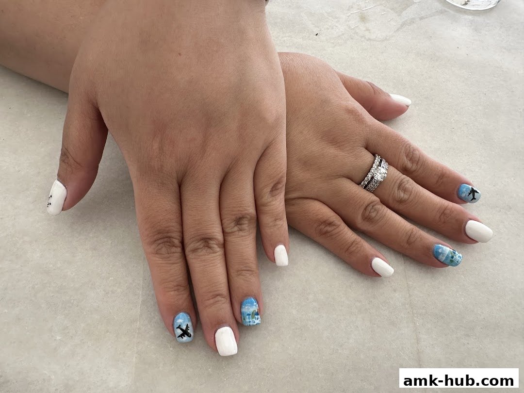 A close-up of hands with white and airplane-themed nail art, showcasing intricate designs.