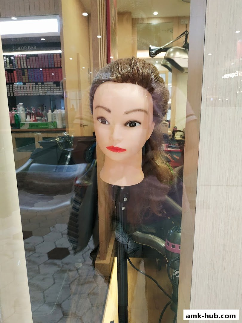 A mannequin head with styled hair is displayed in a salon window.
