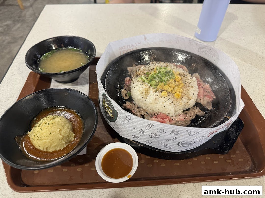 A sizzling hot plate meal with rice, beef, corn, and a side of mashed potatoes and miso soup.