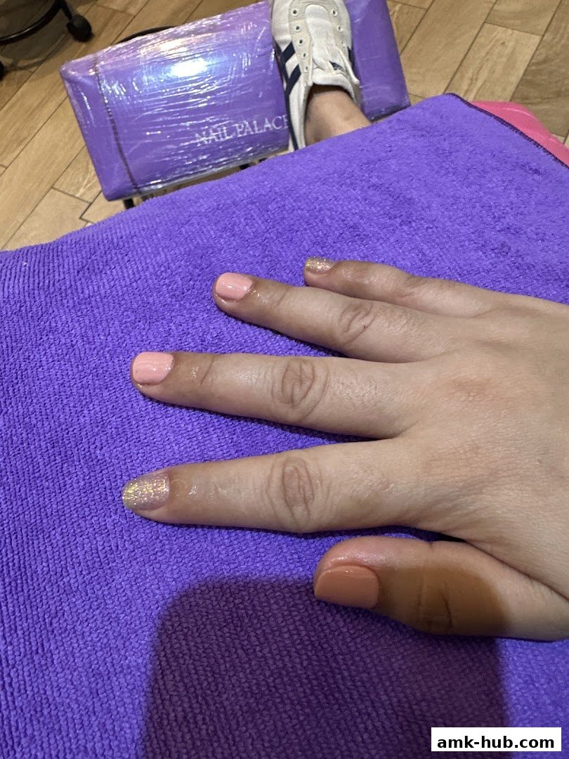 A person's hand with freshly painted nails resting on a purple towel.