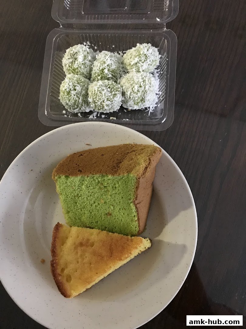 A plate of pandan chiffon cake slices and a container of onde-onde covered in shredded coconut.
