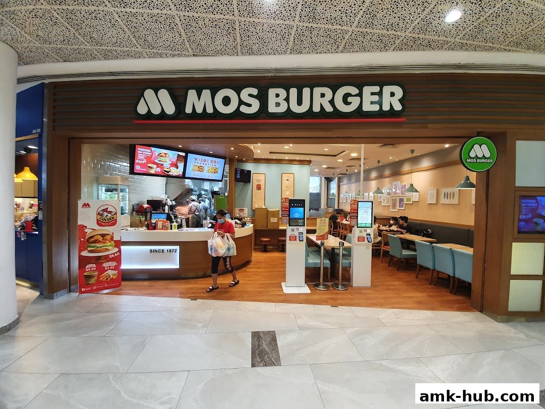 The exterior of a MOS Burger restaurant with a clean, modern design and seating visible inside.