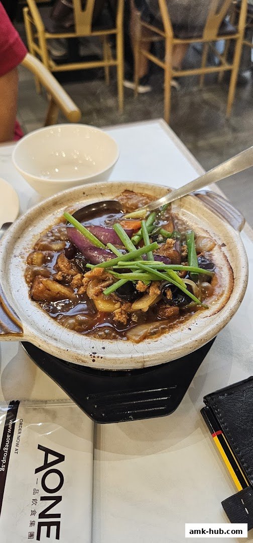 A close-up of a clay pot dish with eggplant, minced meat, and scallions, served at A-One Signature.