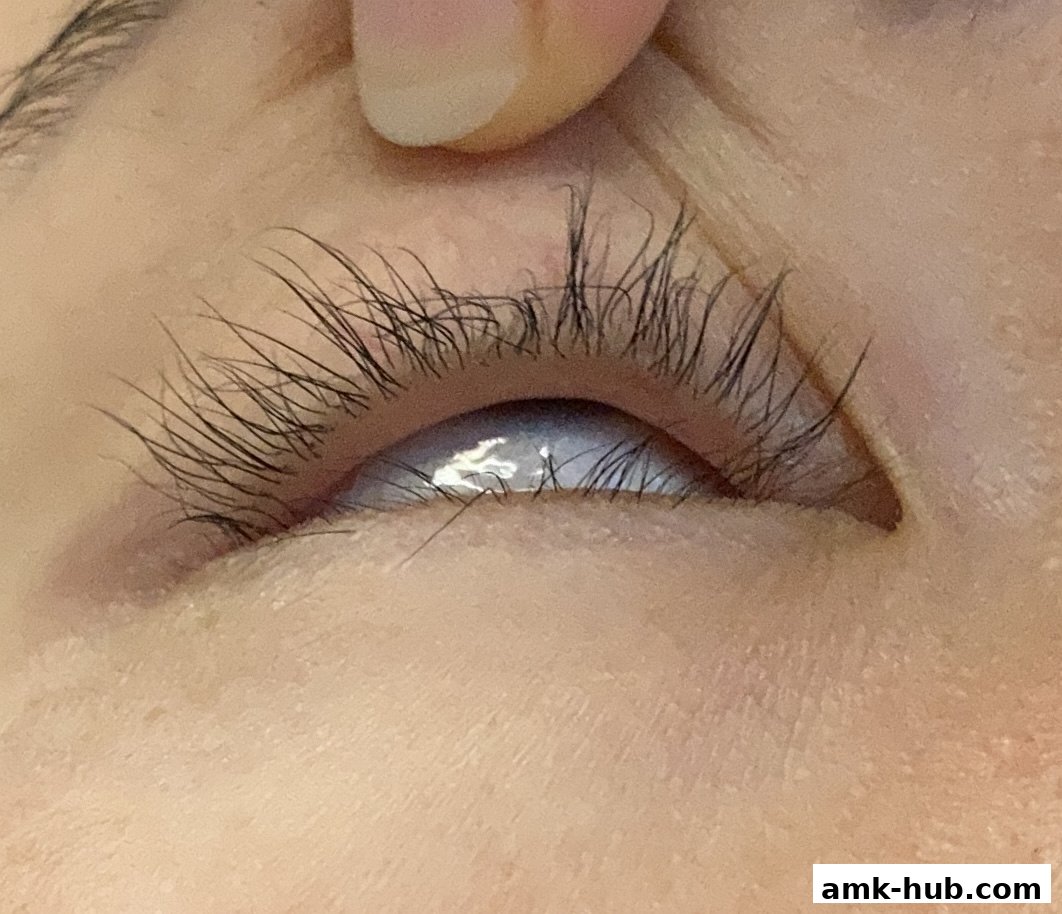 Close-up of a person's eye with long eyelashes and a finger holding the eyelid.