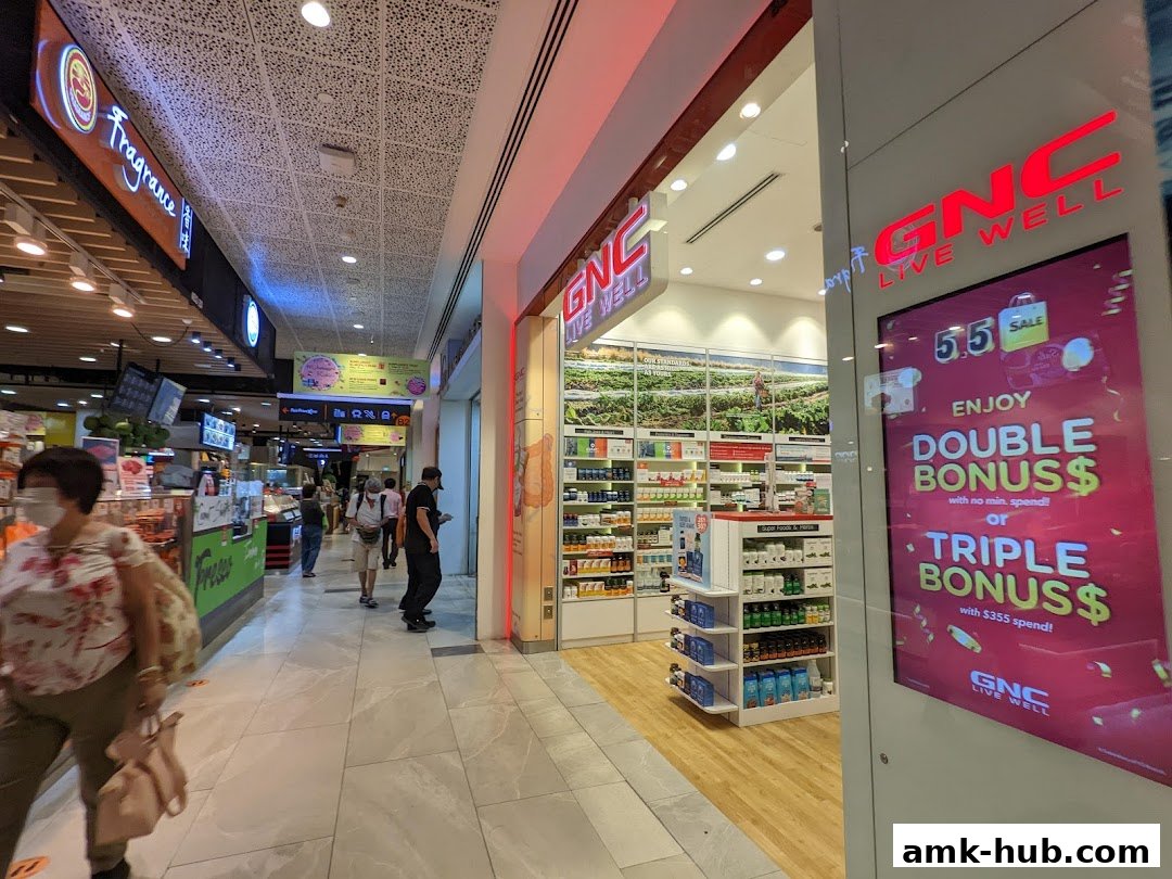 The exterior of a GNC store in a shopping mall, with promotional signage.
