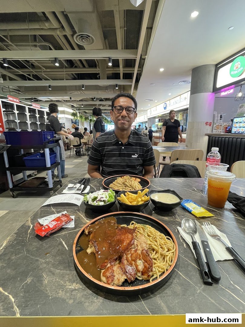 A man sits at a table with a hearty meal of chicken steak, pasta, fries, and salad.