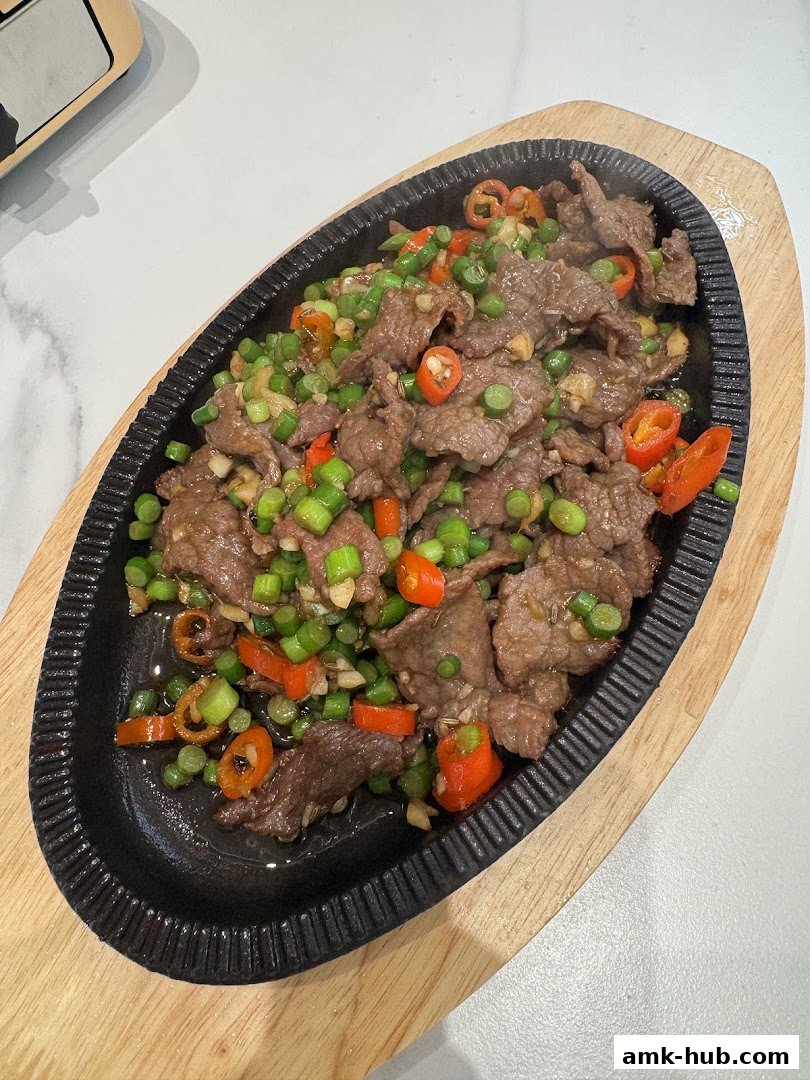 A sizzling hot plate of stir-fried beef with chili and green onions.
